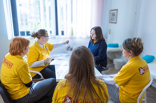 Hier siehst fünf Therapeutinnen konzentriert im Teamgespräch an einem Tisch sitzen.
