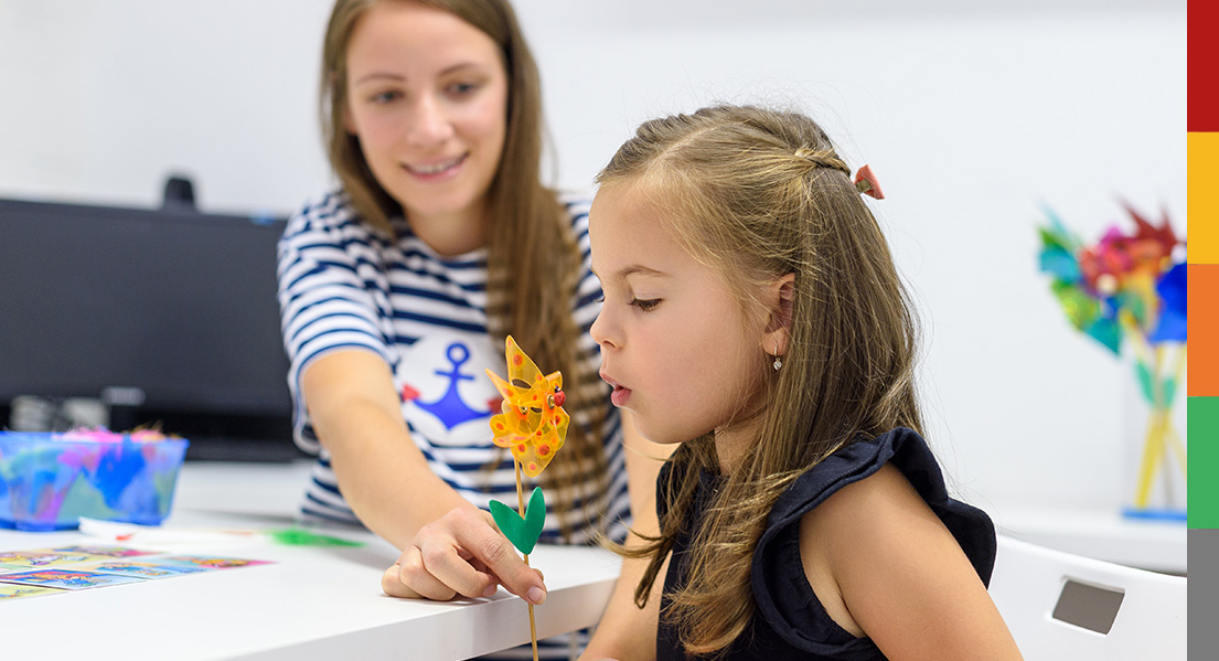 Du siehst hier eine junge Patientin, die spielerisch ein Windrädchen durch Pusten in Bewegung bringt.