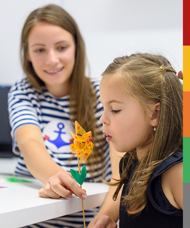 Du siehst hier eine junge Patientin, die spielerisch ein Windrädchen durch Pusten in Bewegung bringt.